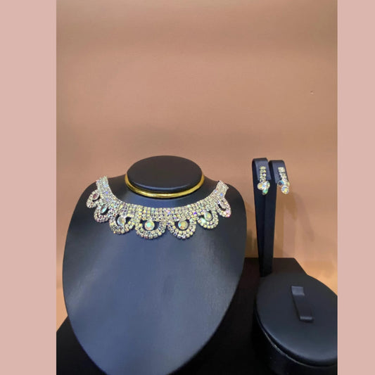 Jewelry set with a necklace and earrings on a black stand against a pink background