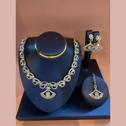 Jewelry set with necklace, earrings, and pendant on a blue stand against a brown background